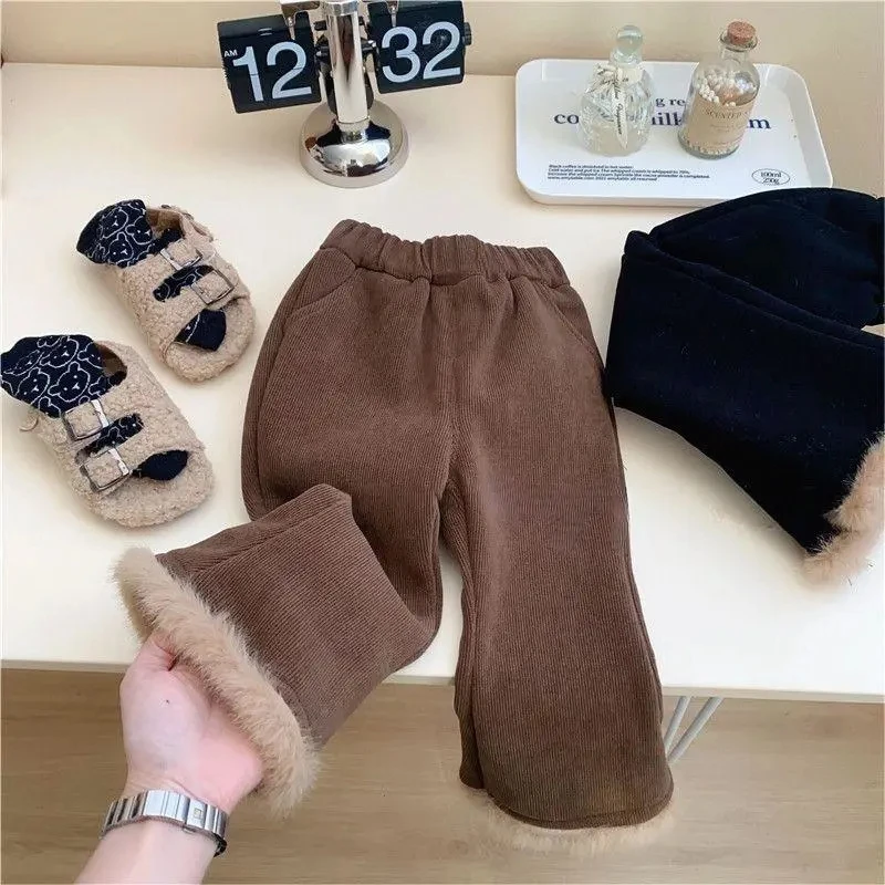Una persona sostiene un par de pantalones marrones con adornos