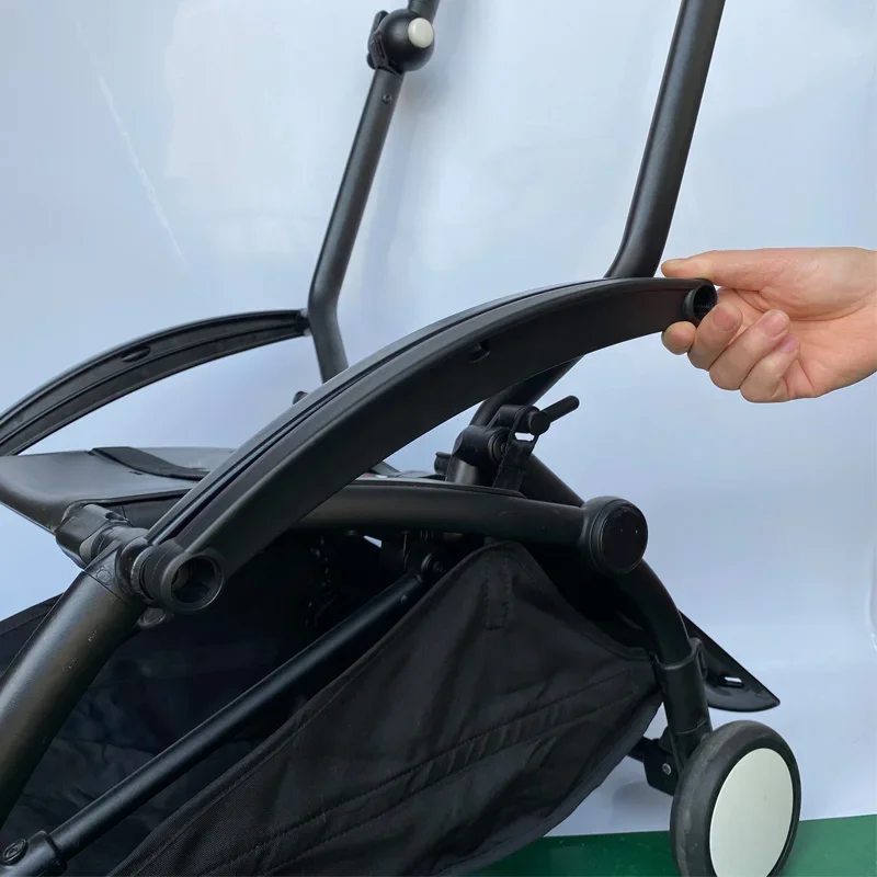 La mano de una persona sujetando el mango de una bicicleta plegable. La bicicleta parece estar plegada o colapsada, lo cual es una característica común de las bicicletas plegables para hacerlas más portátiles y fáciles de guardar.