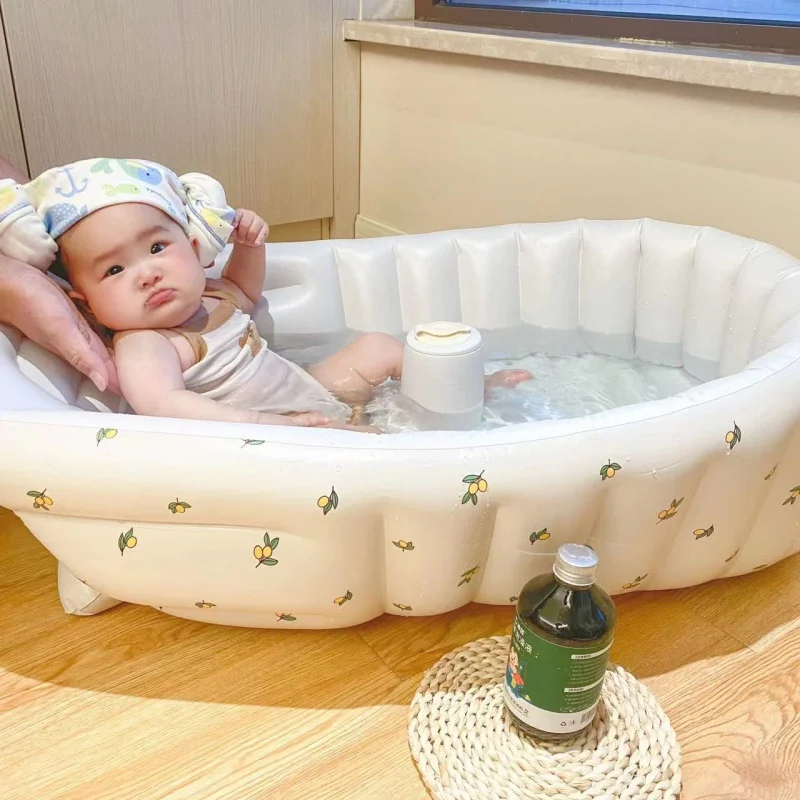Un bebé en una bañera con una botella de jugo al lado