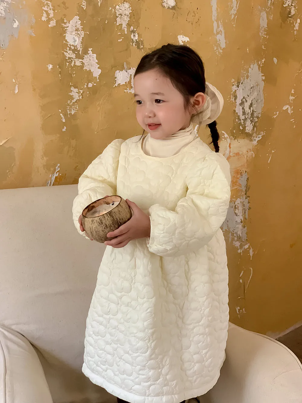 Una niña con un vestido blanco que contiene coco