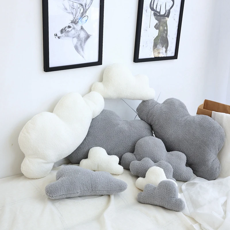 Cojín nube pequeño en gris sobre cama infantil