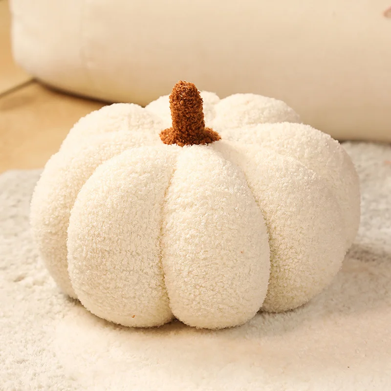 Peluche de calabaza naranja suave sentado sobre superficie clara
