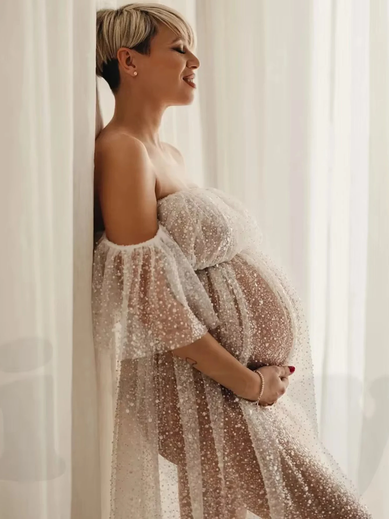 Detalle de lentejuelas plateadas sobre malla transparente en vestido de embarazo