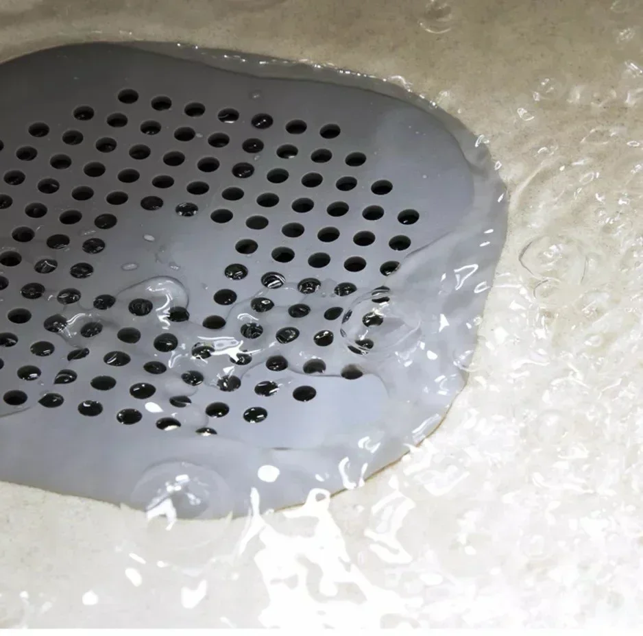 Tapón de desagüe con colador antipelo en uso dentro de un fregadero de cocina reteniendo restos de alimentos