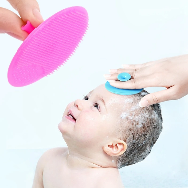 Mano sujetando el cepillo junto a un bebé en la bañera