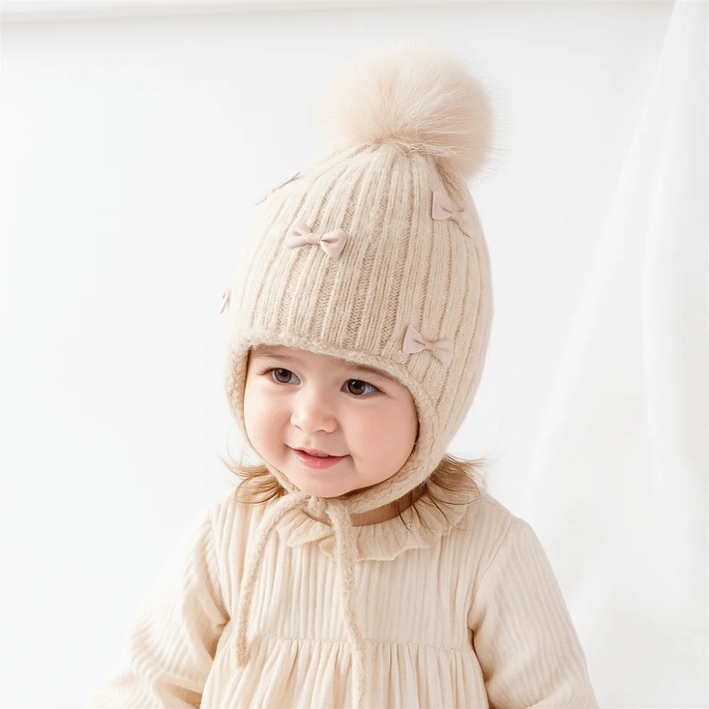 Gorro infantil con lazos y pompones