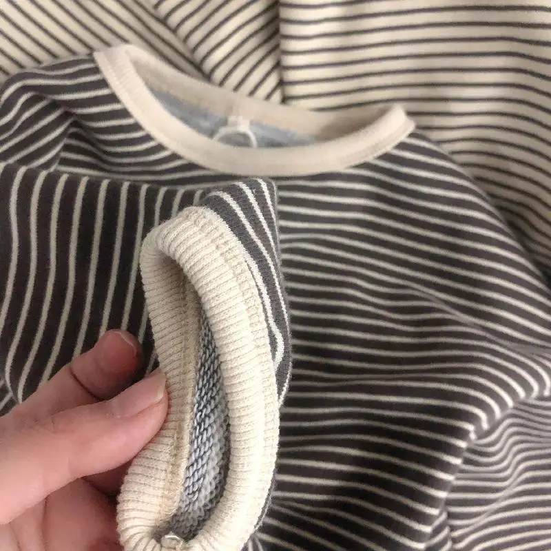 Niña sonriendo mientras ajusta la sudadera frente a un espejo