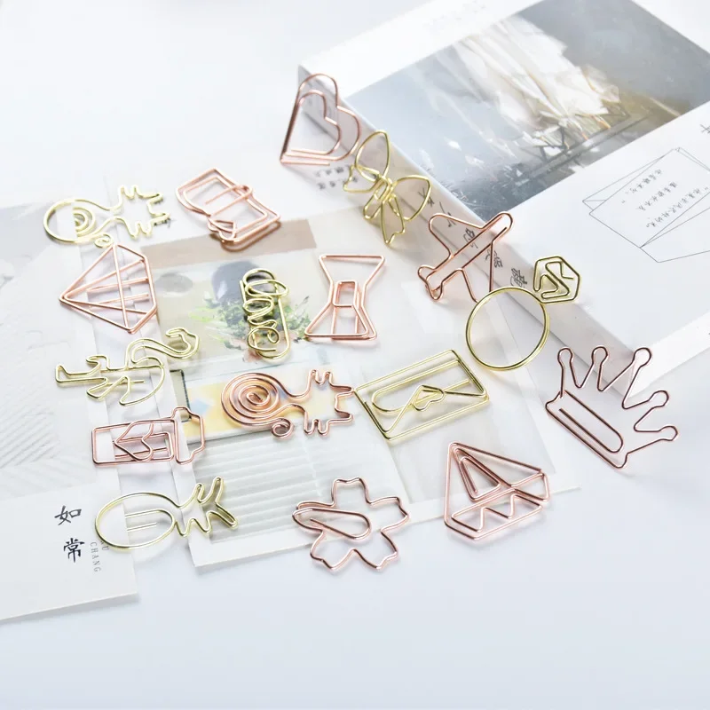 Clip de papel en forma de carpeta color oro rosa sobre fondo claro