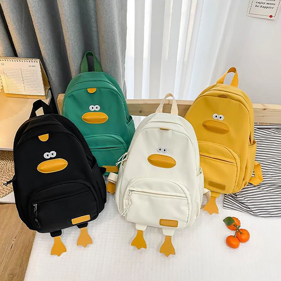 Mochila infantil con pato crema vista frontal mostrando bolsillo frontal y correas ajustables