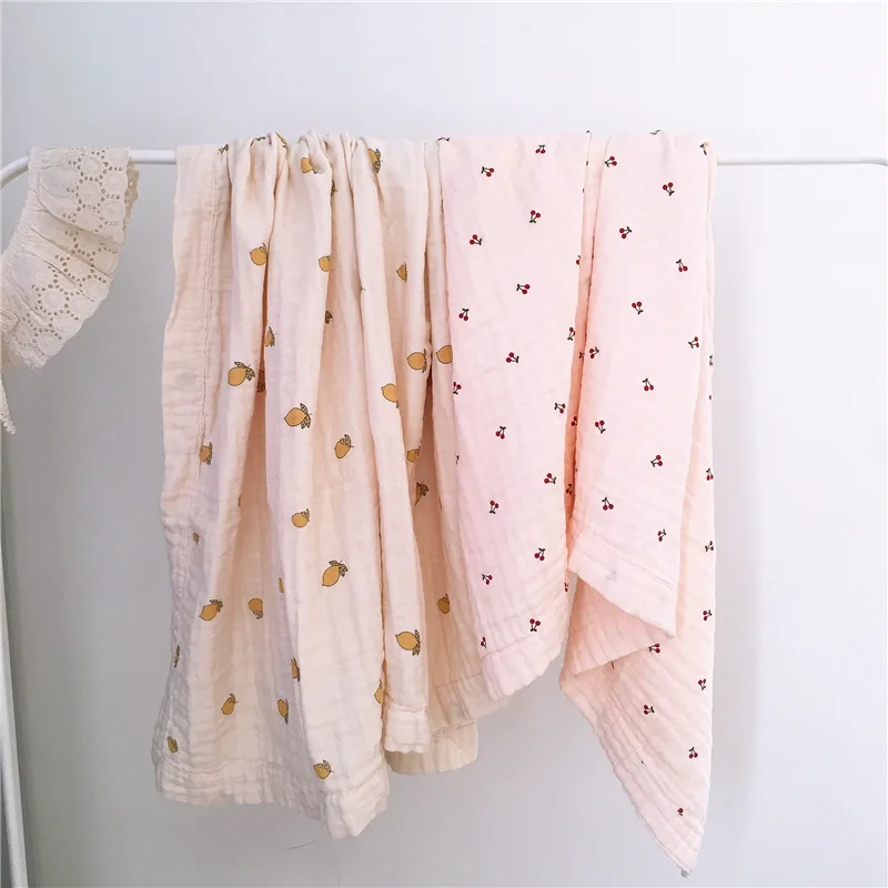 Manta swaddle desplegada con estampado cereza limón flores