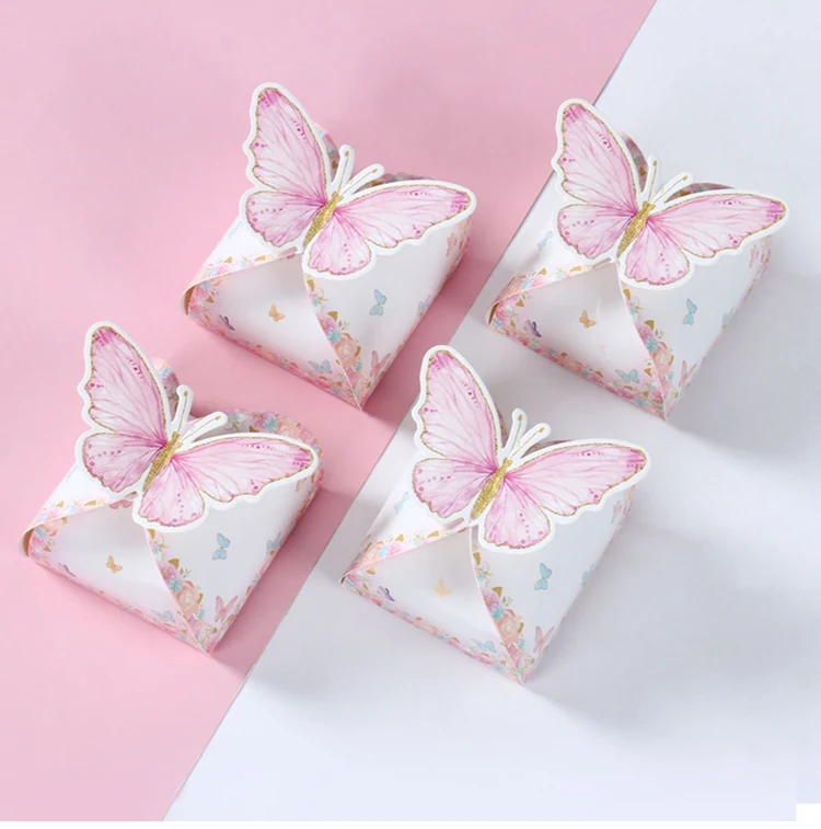 Conjunto de cajas mariposa rosa dispuestas sobre mesa de cumpleaños con tema pastel