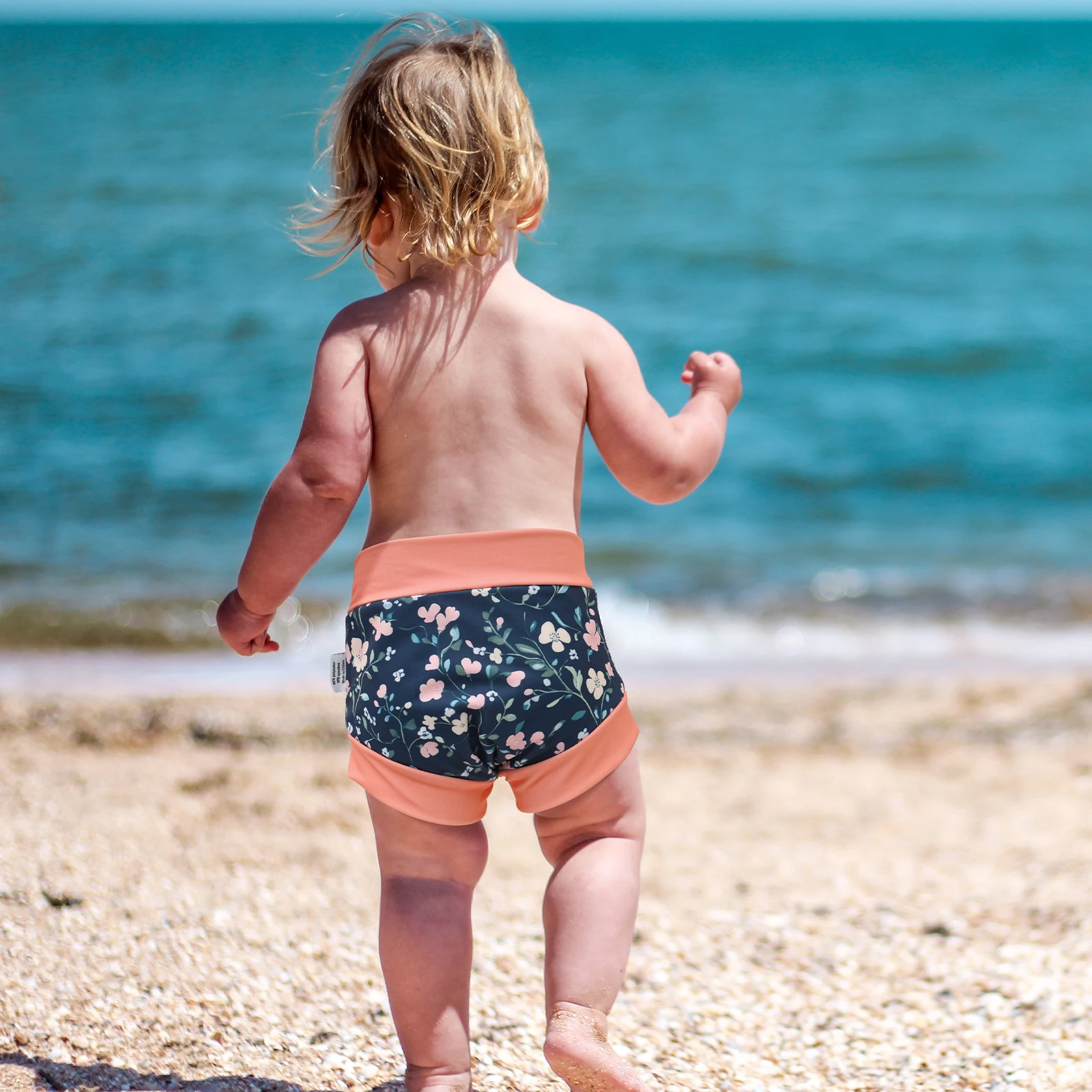 Bebé usando el pañal de natación ALVABABY en la playa