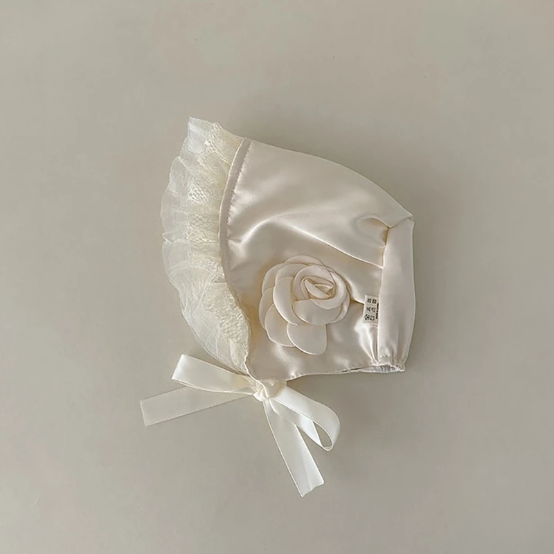 Detalle del encaje floral y satén del gorro para bebé