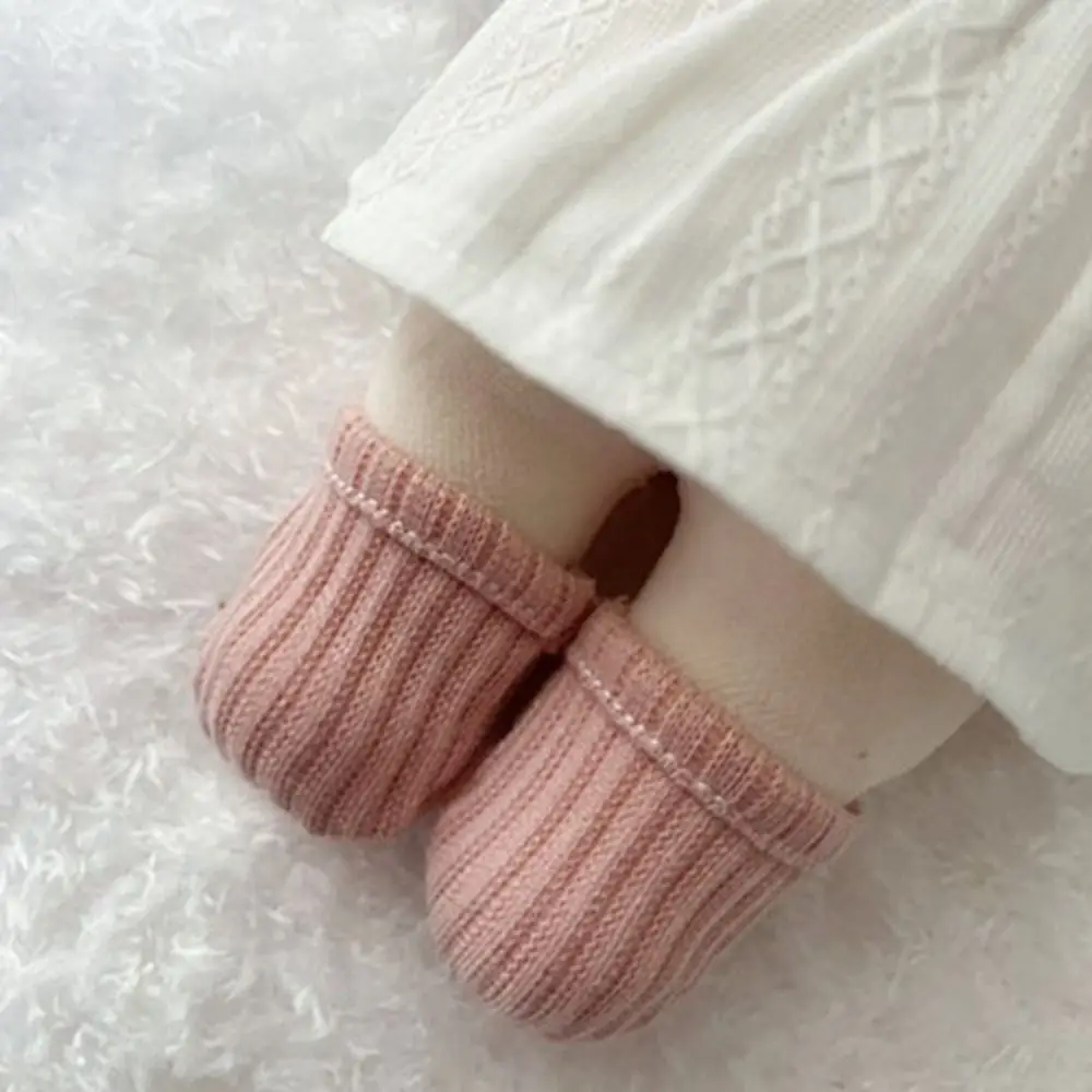 Calcetines grises sobre muñeca de algodón