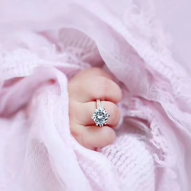 Anillo plateado con cristal brillante en la palma de un bebé