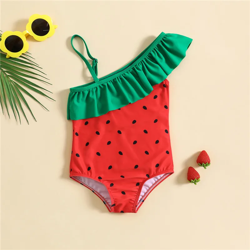 Niña con traje de baño rojo de una pieza con estampado de frutas