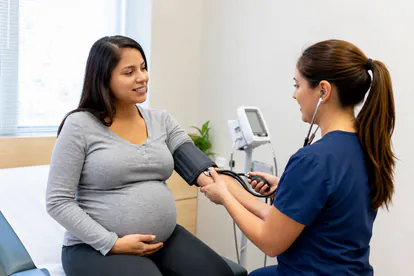 Enfermera mide la presión arterial durante un control prenatal rutinario