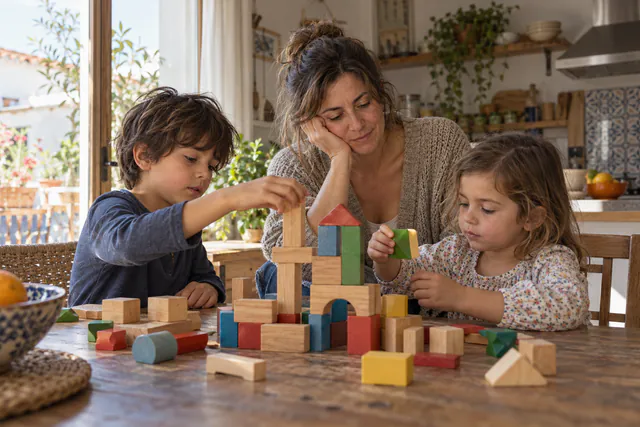 Una madre comparte un juego de bloques con sus hijos pequeños en una mañana tranquila