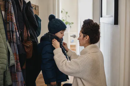 Madre vistiendo a un niño con varias capas antes de salir en invierno.
