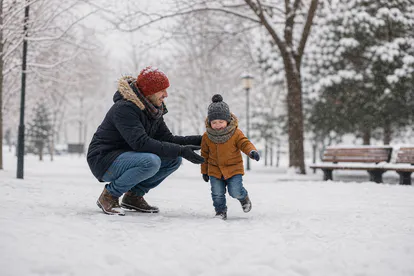 Niño abrigado jugando acompañado en un parque durante el invierno.